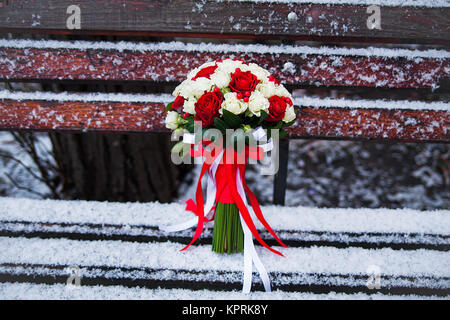 Bouquet de mariage sur un banc de parc d'hiver Banque D'Images