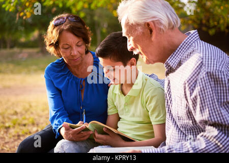 Les grands-parents de l'enfant aidant à faire leurs devoirs scolaires Banque D'Images