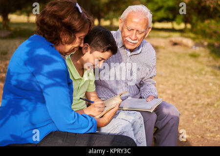 Papi et mamie aidant petit-fils à faire ses devoirs Banque D'Images