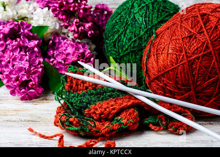 Boules de fil de laine à tricoter et branches de fleurs lilas Banque D'Images