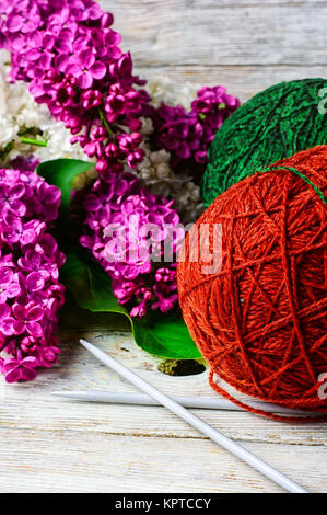 Boules de fil de laine à tricoter et branches de fleurs lilas Banque D'Images