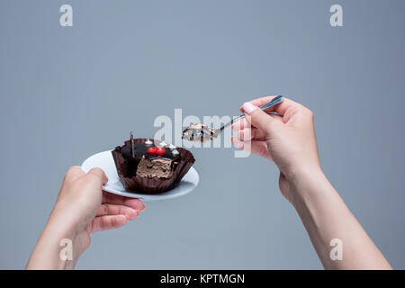 Garder les mains des femmes avec cuillère gâteau sur gris Banque D'Images