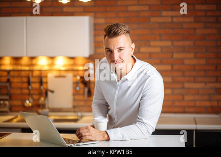 Assis dans son bureau de l'entrepreneur holding tasse de café smiling to camera Banque D'Images