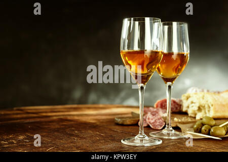 Deux verres de sherry servi avec de délicieuses tapas espagnoles traditionnelles d'olives, de salami et de pain frais, sur une vieille table en bois avec copie espace Banque D'Images
