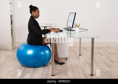 Businesswoman Sitting on Fitness Ball in Office Banque D'Images