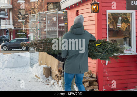 Montréal, Canada - 16 décembre 2017 : un homme porte un arbre de Noël Banque D'Images