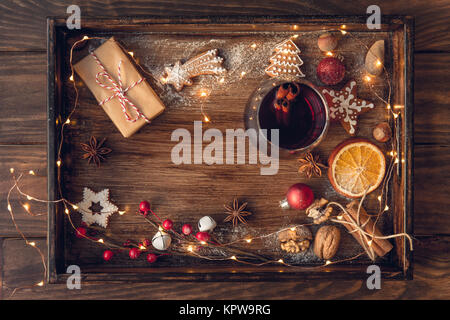 Vin chaud ou d'un poinçon dans le verre, les biscuits de Noël, les oranges et sec phares sur fond foncé vintage rustique, vue du dessus, frontière. Concept de Noël. Banque D'Images