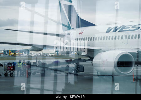 La photo artistique de vérifié dans les bagages d'être chargé dans un avion de WestJet à l'aéroport international de Victoria, BC, Canada 2017 Banque D'Images