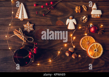 Vin chaud ou d'un poinçon dans le verre, les biscuits de Noël, les oranges et sec phares sur fond foncé vintage rustique, vue du dessus, frontière. Concept de Noël. Banque D'Images