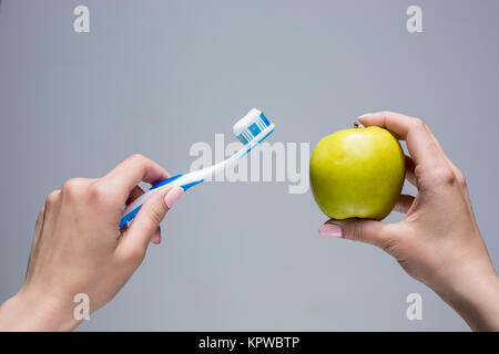 Brosse à dents et apple en femme&# 39 sur les mains de Gray Banque D'Images