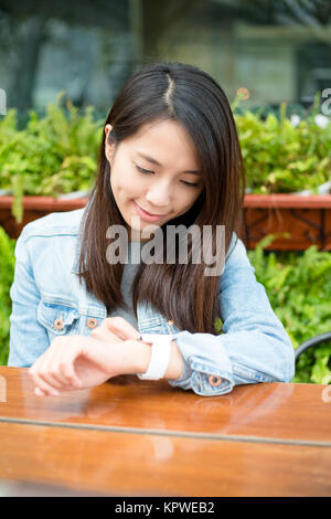 Femme l'utilisation de smart watch at outdoor cafe Banque D'Images