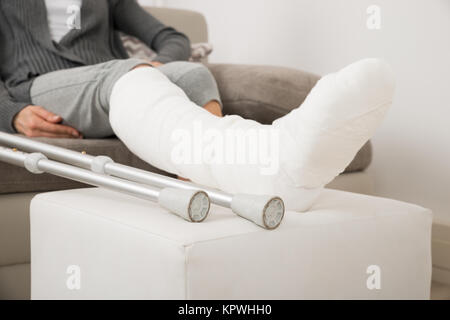 Femme avec la jambe plâtrée Sitting on Couch Banque D'Images