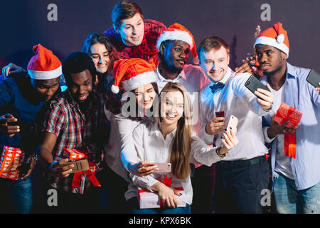 Les filles et les gars à Santa hats faisant partie de selfies. Noël, nouvel an concept Banque D'Images