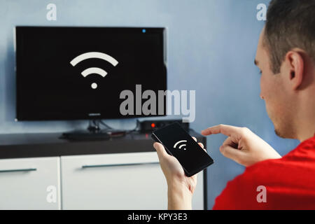 La connectivité entre smart tv et smart phone via une connexion wifi. Contrôler votre TV avec votre smartphone. Le wifi de l'écran du téléphone et le Banque D'Images