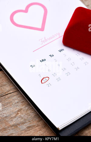 Calendrier indiquant la date 14 février. Red Rose, coeurs et boîte-cadeau sur table en bois. Banque D'Images