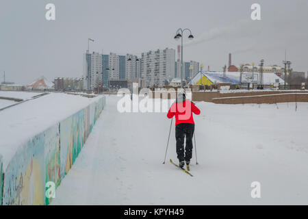 Jeune homme ski dans un manteau rouge le long de la rivière Banque D'Images