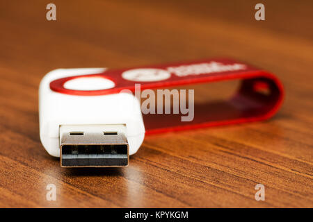 Vue rapprochée d'un connecteur de lecteur Flash USB blanc à tête rouge, sur un fond de bois Banque D'Images