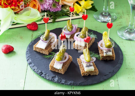 Les canapés avec le pain de seigle, le hareng et les cornichons sur une table de fête. Valentine's day concept ou mariage. Banque D'Images