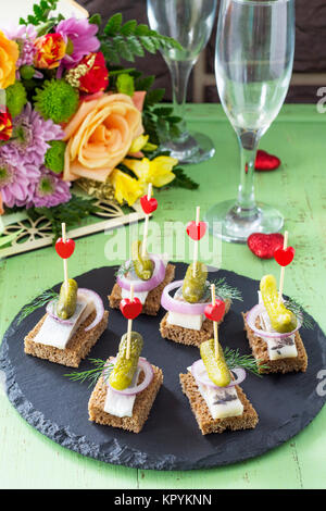 Les canapés avec le pain de seigle, le hareng et les cornichons sur une table de fête. Valentine's day concept ou mariage. Banque D'Images