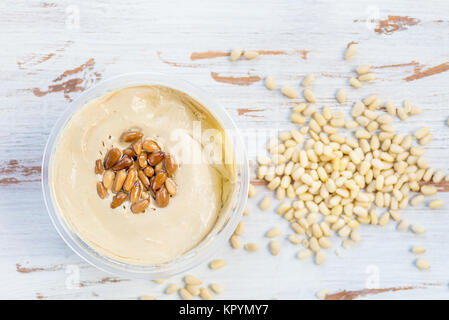 L'hummus classique fabriqué à partir de pois chiches avec les noix de pin sur le dessus en bois, fond rustique, vue du dessus Banque D'Images