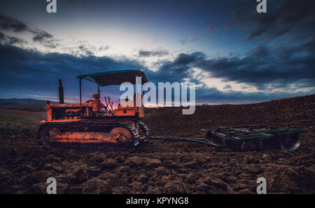 Old rusty tracteur dans un champ sur le coucher du soleil.image HDR. Banque D'Images