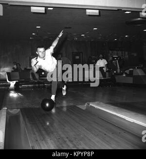Années 1960, historique, un bowling, un homme tenant une balle bolwling sur le point de laisser tomber au fond d'une voie dix broches bolwling alley, USA. Banque D'Images