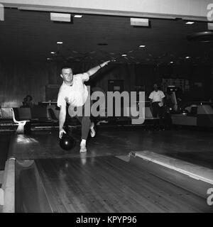 Années 1960, historique, un bowling, un homme tenant une balle bolwling sur le point de laisser tomber au fond d'une voie dix broches bolwling alley, USA. Banque D'Images