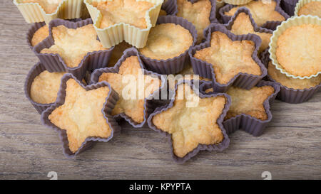 Petits gâteaux de pâte de noix de coco sucrée. Close-up of cookies tout juste sortis du four dans les moules en silicone décoratif sur un fond de bois. Banque D'Images