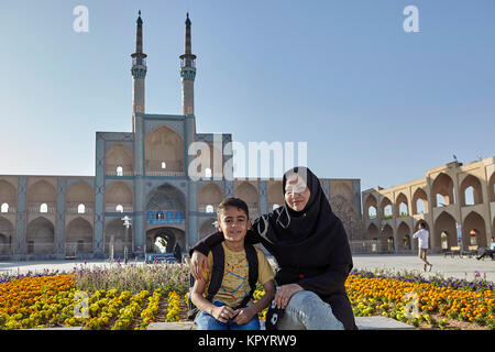 Yazd, Iran - avril 21, 2017 : femme dans le tchador islamique et son fils assis sur le banc en face d'Amir Chakhmaq complexe. Banque D'Images