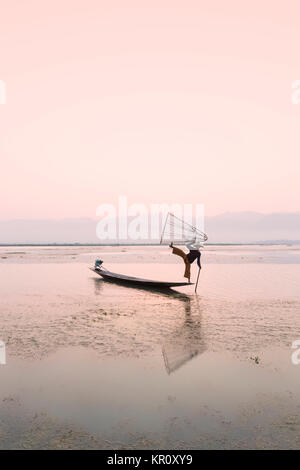 Lac Inle pêcheur debout sur un bateau longtail dans la position d'aviron jambe distinctif utilisé par l'ethnie Intha, lac Inle, Myanmar Banque D'Images