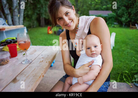Assis dans le jardin de la mère avec son bébé garçon Banque D'Images