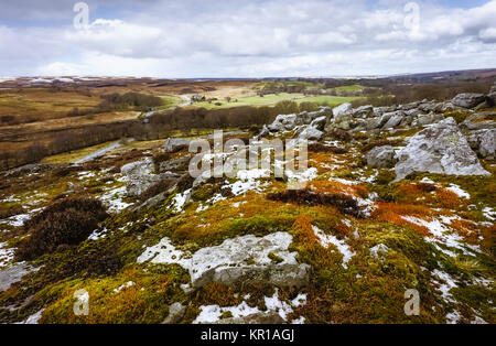 La diffusion de la lumière de neige sur le North York Moors avec vue sur les roches, Heather, et de terres agricoles en hiver près de Goathland, Yorkshire, UK. Banque D'Images