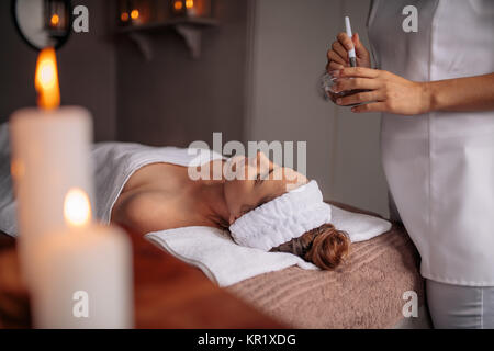 Femme couchée sur table avec un masque de beauté la préparation dans un bol. Woman getting a facial treatment in Beauty Spa. Banque D'Images