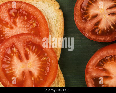 Tranches de tomate sur le pain doré sur fond vert Banque D'Images