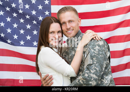 Soldat mâle avec sa femme en face de drapeau américain Banque D'Images