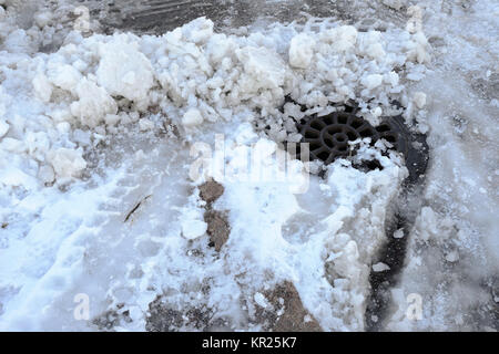 Un puits d'eaux usées pluviales couverte de neige et de glace en hiver Banque D'Images