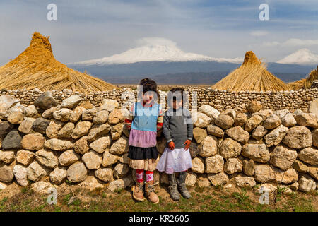 Deux jeunes filles locales avec les deux sommets du Mont Ararat et des piles de roseaux en arrière-plan à Agri, Turquie. Banque D'Images