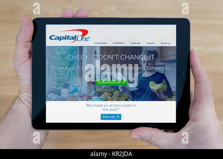 Un homme regarde le Capital One Bank site sur son iPad tablet device, tourné contre une table en bois page contexte (usage éditorial uniquement) Banque D'Images