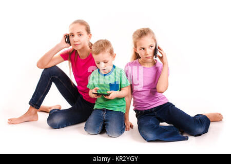 Groupe des petits enfants à l'aide de dispositifs électroniques isolé sur blanc. Banque D'Images