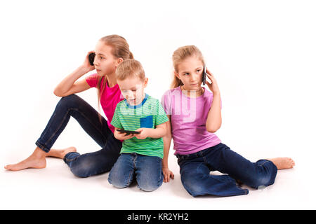 Groupe des petits enfants à l'aide de dispositifs électroniques isolé sur blanc. Banque D'Images