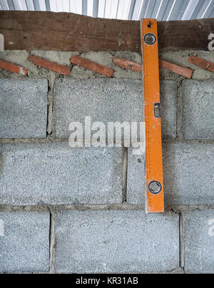 Ancien dirigeant de niveau est accroché sur le mur de brique pour la mesure dans la maison inachevée. Banque D'Images