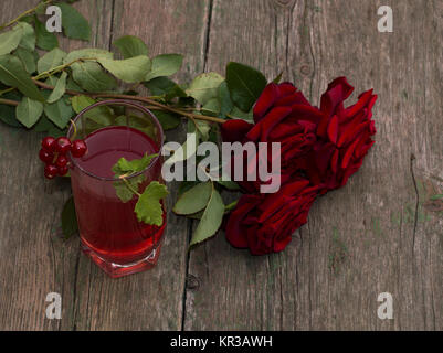 Bouquet de belles roses et verre de jus de couleur rouge Banque D'Images