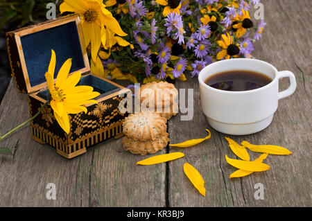 Cercueil ouvert, café, biscuits, des pétales et des fleurs sauvages sur une vieille table Banque D'Images