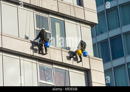 Deux laveurs de vitres à l'aide de techniques d'accès sur corde sur un bâtiment près de l'Arène, Birmingham, Angleterre, RU, Banque D'Images