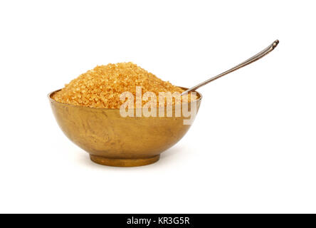 Près d'un bol en métal bronze plein de sucre de canne brut avec un cuillère, isolé sur fond blanc, low angle view Banque D'Images