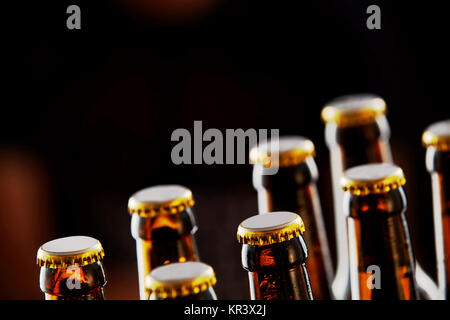 Deux rangées de bouteilles de bière brune non ouvert dans une diagonale gros plan sur un fond sombre avec copie espace Banque D'Images