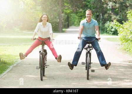 Heureux Couple Riding Bicycle In Park Banque D'Images