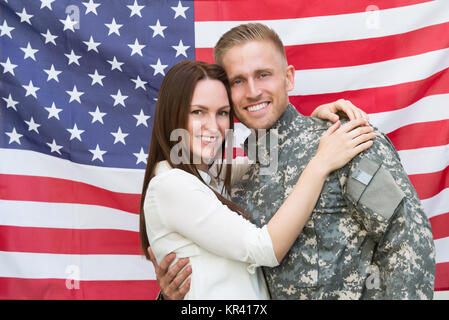 Soldat mâle avec sa femme en face de drapeau américain Banque D'Images