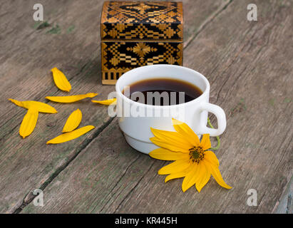 Cercueil, pétales, fleur jaune et le café, sur une table en bois, une nature morte Banque D'Images