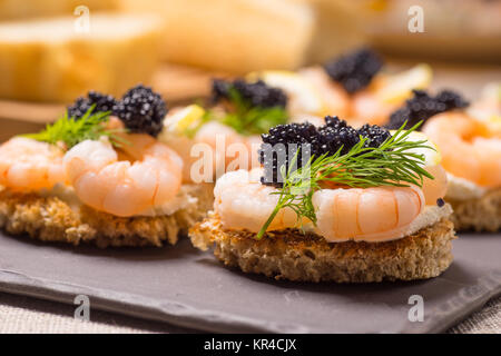 Apéritif crevettes servi sur pain grillé et servi sur une plaque en ardoise Banque D'Images